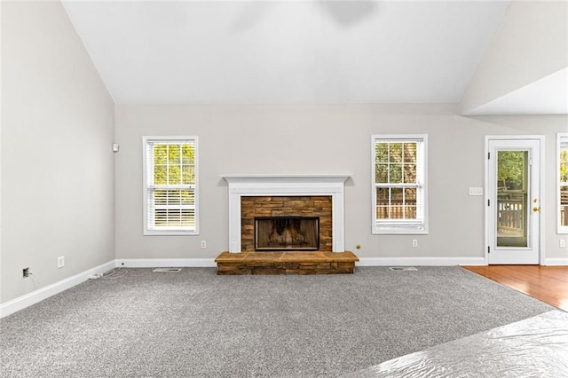 unfurnished living room featuring vaulted ceiling, carpet floors, a fireplace, and baseboards