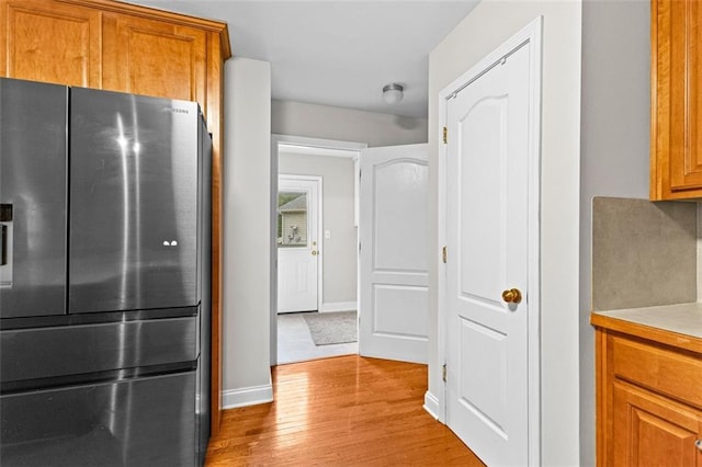 kitchen with light countertops, brown cabinetry, wood finished floors, and stainless steel fridge with ice dispenser