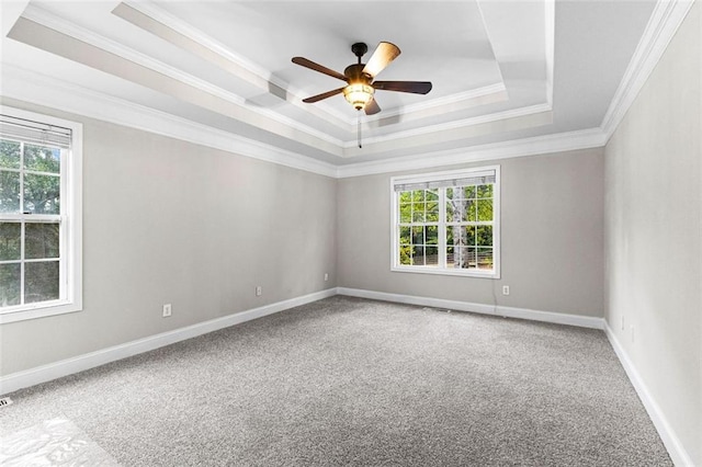 unfurnished room with carpet floors, a ceiling fan, baseboards, a tray ceiling, and crown molding