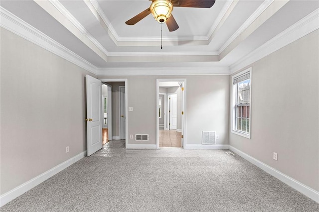 unfurnished bedroom featuring carpet floors, visible vents, a tray ceiling, and baseboards