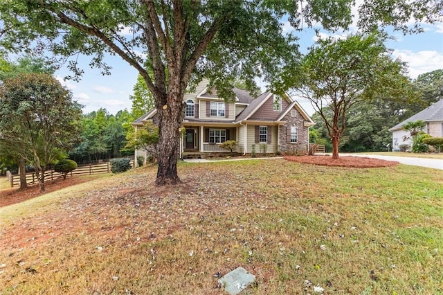 craftsman inspired home with stone siding, fence, and a front lawn