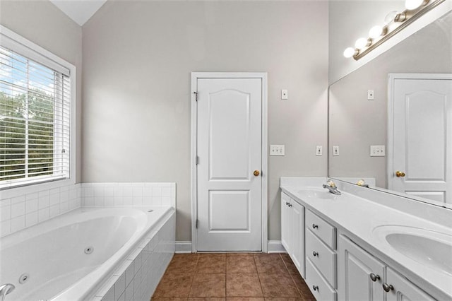 bathroom featuring double vanity, baseboards, a tub with jets, tile patterned flooring, and a sink