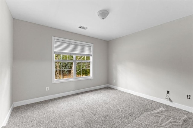 spare room featuring baseboards, visible vents, and carpet flooring