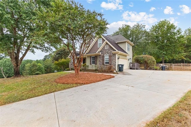 craftsman inspired home with a garage, fence, concrete driveway, stone siding, and a front lawn