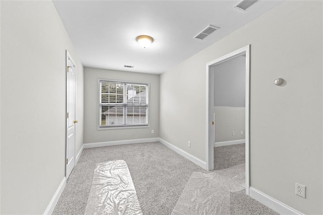 carpeted spare room with visible vents and baseboards