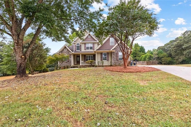 view of front of property with stone siding, fence, and a front lawn