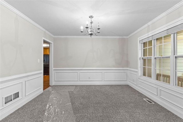 carpeted empty room with visible vents, a decorative wall, a notable chandelier, and ornamental molding