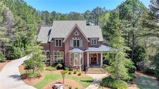 4505 Whitestone Way, Suwanee, GA 30024 - english style home featuring a standing seam roof, covered porch, metal roof, stone siding, and french doors