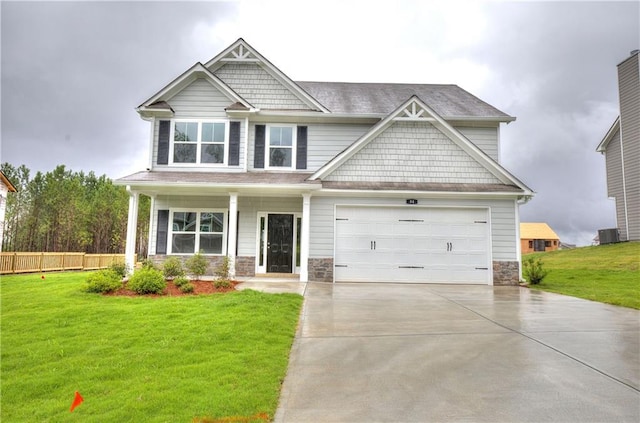 craftsman inspired home with a front yard, stone siding, fence, and concrete driveway