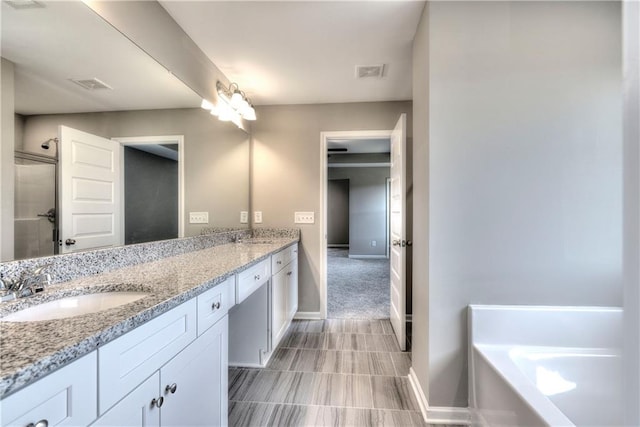 full bath with double vanity, baseboards, visible vents, a garden tub, and a sink