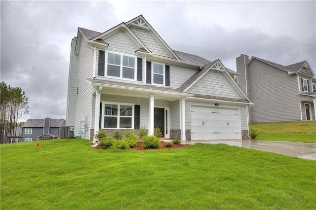 craftsman-style home with driveway, central AC unit, stone siding, an attached garage, and a front lawn