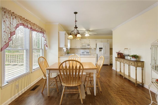 dining space featuring dark wood finished floors, visible vents, baseboards, and ornamental molding