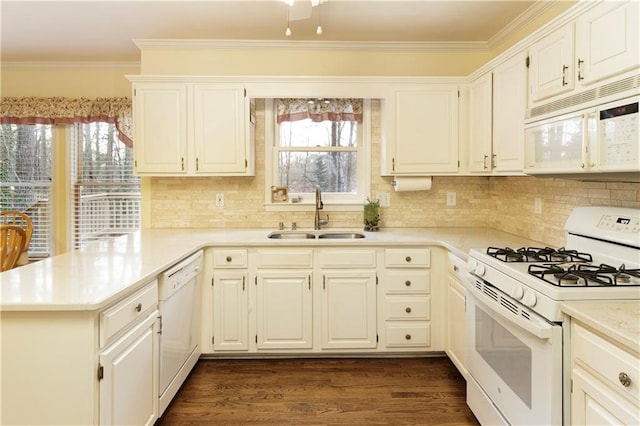 kitchen with white appliances, a peninsula, a sink, dark wood-type flooring, and crown molding