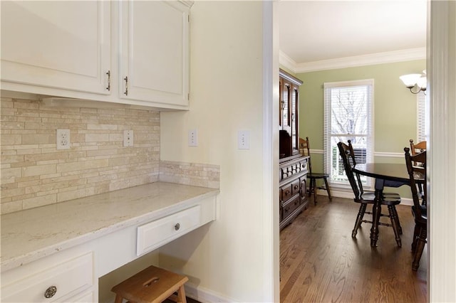 kitchen featuring light stone counters, dark wood-style flooring, white cabinets, crown molding, and tasteful backsplash