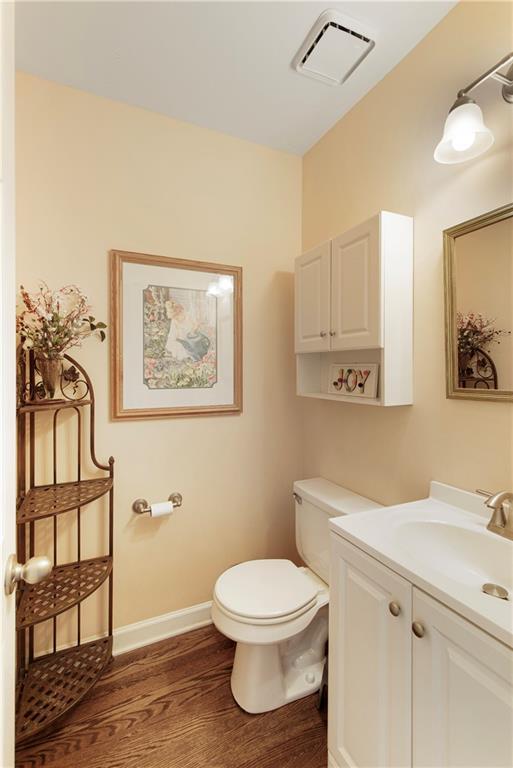 bathroom with visible vents, toilet, wood finished floors, baseboards, and vanity