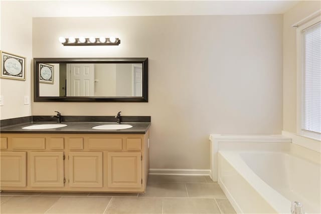 bathroom with tile patterned floors, a garden tub, double vanity, and a sink