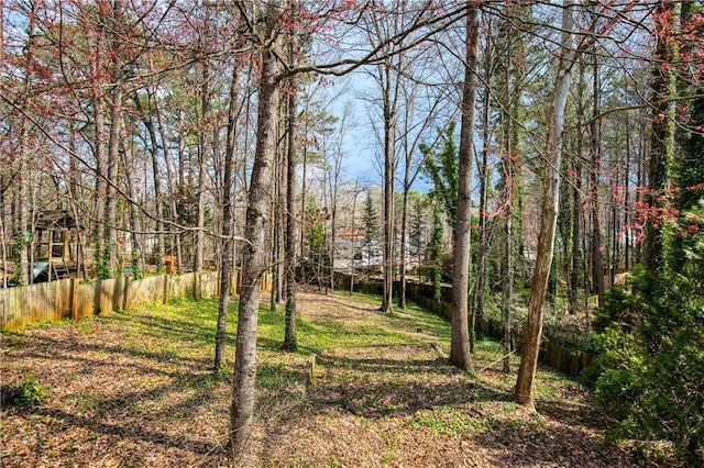 view of yard with a forest view and fence