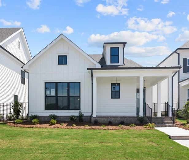 view of front of house featuring board and batten siding, covered porch, and a front lawn