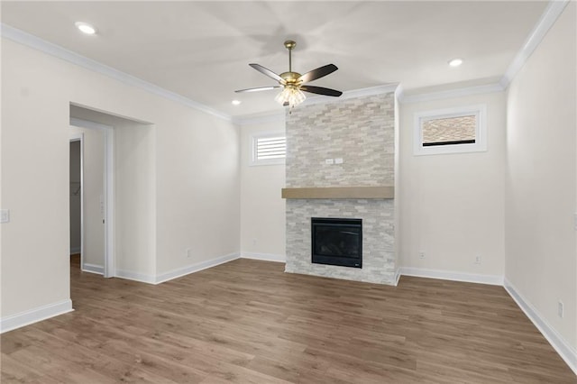 unfurnished living room featuring ornamental molding, a stone fireplace, and wood finished floors