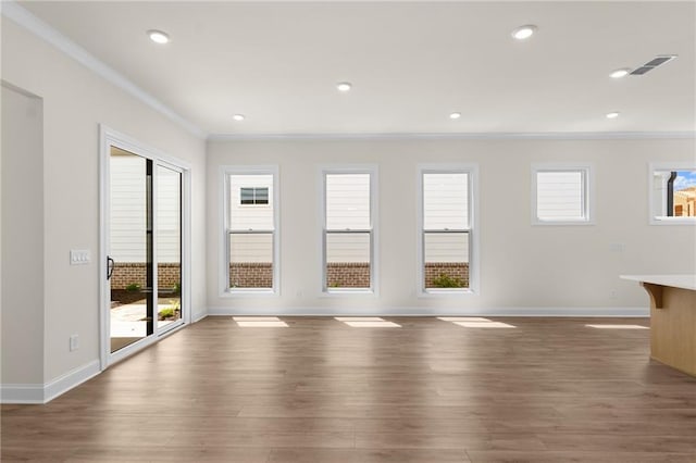 unfurnished living room with visible vents, crown molding, baseboards, and wood finished floors