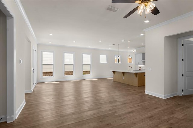 unfurnished living room featuring recessed lighting, visible vents, ornamental molding, a sink, and wood finished floors