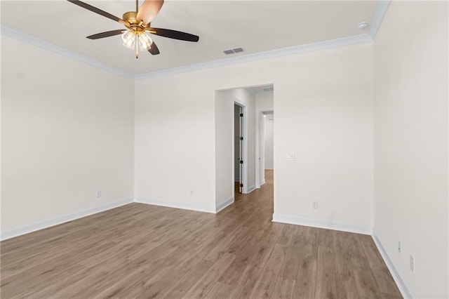 spare room featuring ceiling fan, visible vents, baseboards, ornamental molding, and light wood finished floors