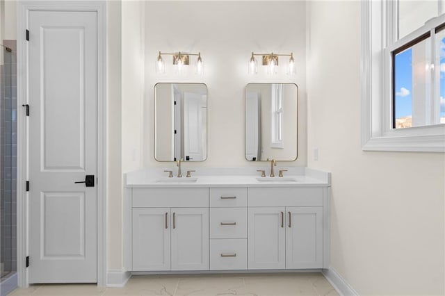 bathroom with marble finish floor, a sink, baseboards, and double vanity