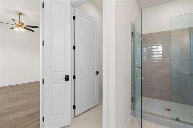 full bathroom featuring ceiling fan, a stall shower, wood finished floors, and baseboards