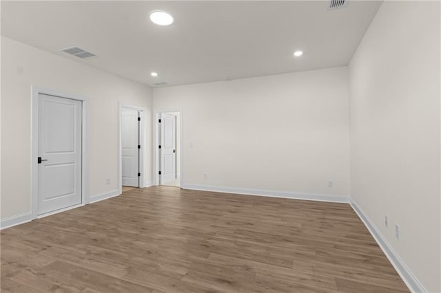 spare room with baseboards, wood finished floors, visible vents, and recessed lighting