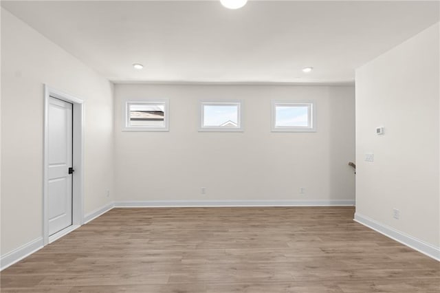 empty room featuring light wood-style floors, baseboards, and a wealth of natural light