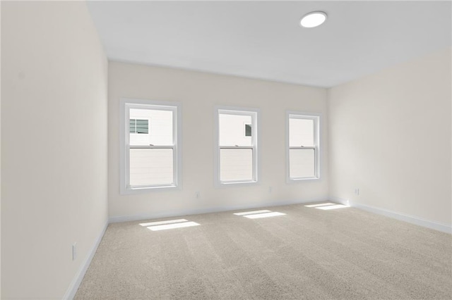 carpeted spare room with plenty of natural light and baseboards