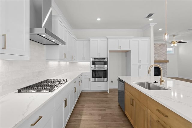 kitchen featuring visible vents, appliances with stainless steel finishes, a sink, wall chimney range hood, and ceiling fan