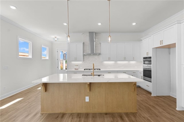 kitchen with wall chimney exhaust hood, decorative backsplash, crown molding, and light wood-style flooring