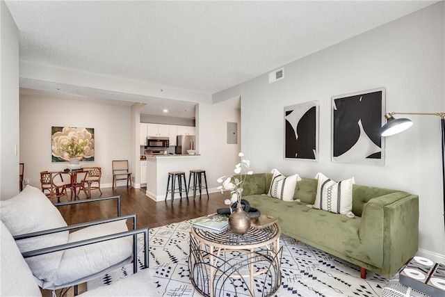 living area featuring visible vents, a textured ceiling, light wood-type flooring, and baseboards