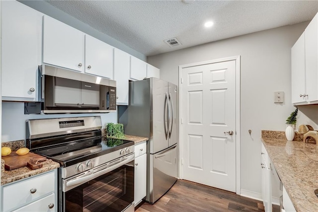 kitchen with visible vents, dark wood-style flooring, appliances with stainless steel finishes, a textured ceiling, and white cabinetry