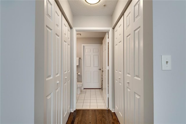 hall with a textured ceiling and wood finished floors