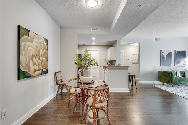 dining room featuring visible vents, baseboards, dark wood-type flooring, and a textured ceiling