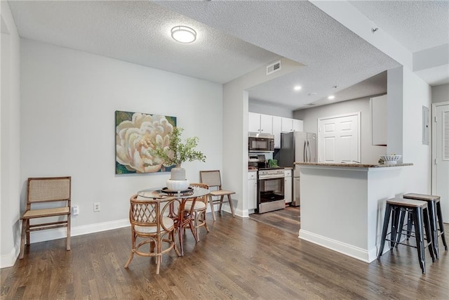 dining room featuring visible vents, a textured ceiling, dark wood-type flooring, and baseboards