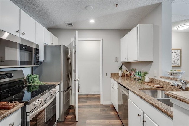 kitchen featuring a sink, a textured ceiling, wood finished floors, white cabinetry, and appliances with stainless steel finishes