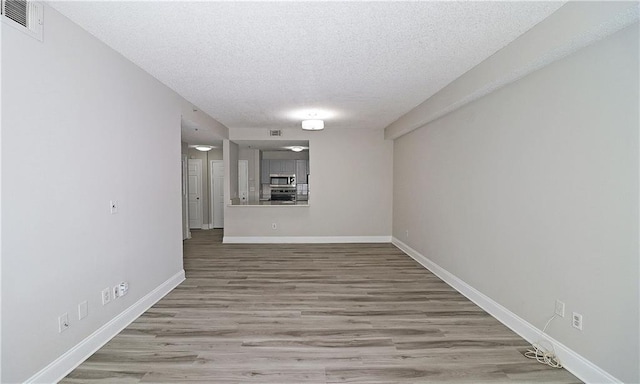 1074 Peachtree Walk NE Unit B 216, Atlanta, GA 30309 - empty room with visible vents, a textured ceiling, baseboards, and wood finished floors