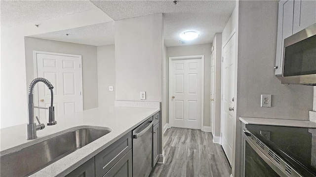 1074 Peachtree Walk NE Unit B 216, Atlanta, GA 30309 - kitchen featuring light stone counters, a sink, stainless steel appliances, light wood-style floors, and a textured ceiling