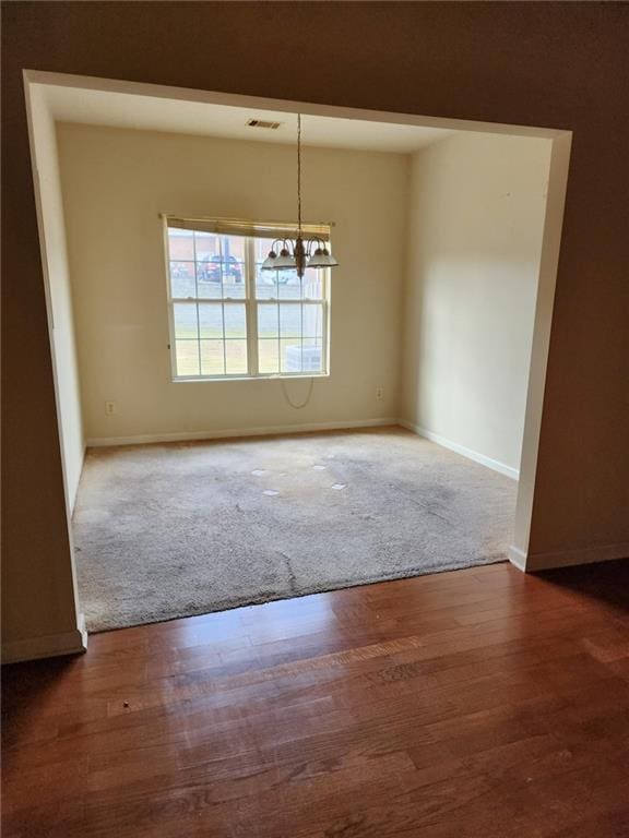 unfurnished room with hardwood / wood-style floors and a notable chandelier