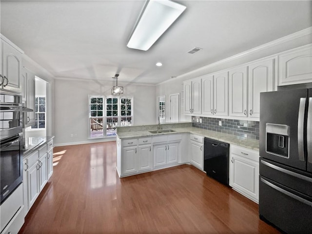 kitchen with visible vents, a peninsula, stainless steel appliances, white cabinetry, and a sink