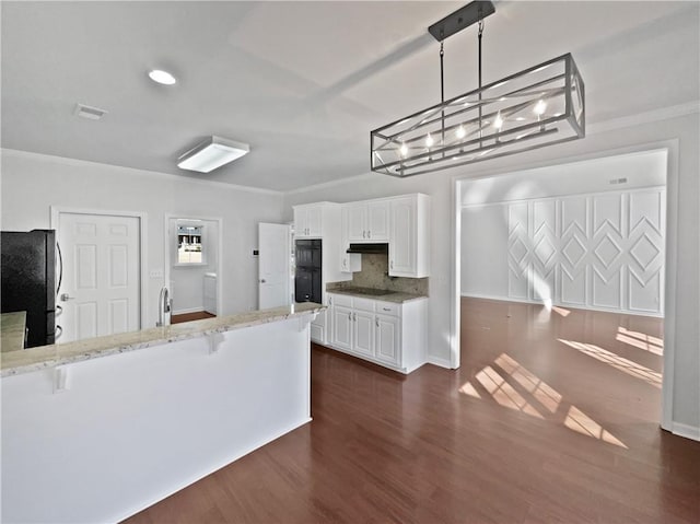 kitchen with dark wood-type flooring, crown molding, black appliances, a kitchen bar, and white cabinetry