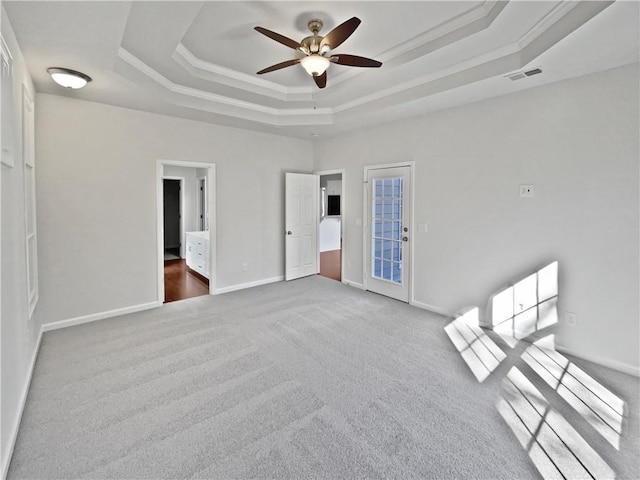 unfurnished bedroom featuring baseboards, visible vents, a raised ceiling, carpet, and access to outside