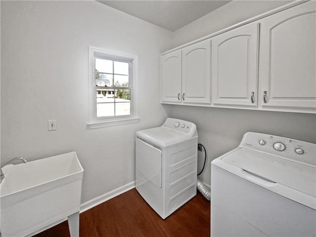 laundry area featuring dark wood-style flooring, washing machine and clothes dryer, cabinet space, a sink, and baseboards