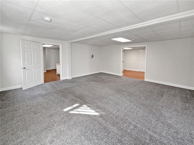 finished basement with carpet floors, baseboards, and a paneled ceiling