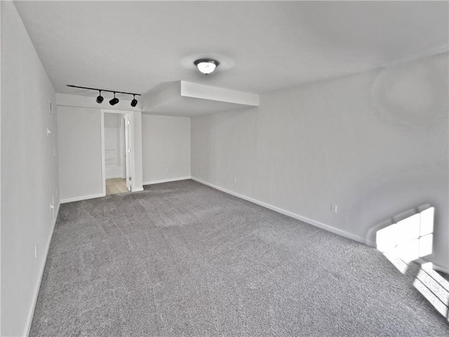 carpeted spare room featuring track lighting, radiator heating unit, and baseboards