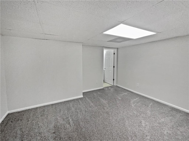 carpeted spare room featuring a paneled ceiling and baseboards