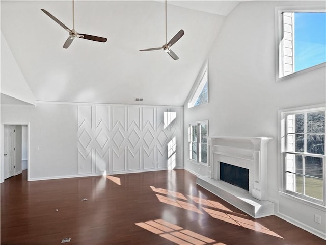 unfurnished living room with a fireplace with raised hearth, wood finished floors, visible vents, and baseboards